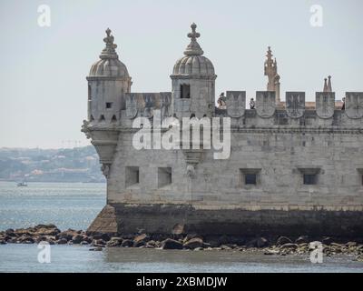 Primo piano di una storica torre in pietra sul lungomare con impressionanti dettagli architettonici e mare calmo, Lisbona, portogallo Foto Stock