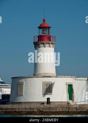 Un faro con un edificio bianco e tetto rosso si erge nel porto sotto un cielo azzurro, ibiza, il Mar mediterraneo, la spagna Foto Stock