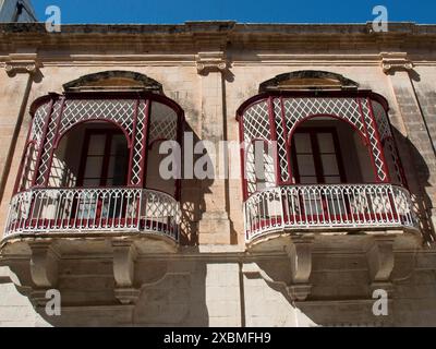 Due balconi in ferro decorati e decorativi di fronte a una storica parete in pietra con finestre, mdina, Mar mediterraneo, malta Foto Stock