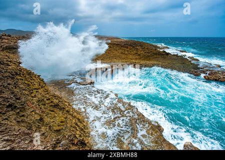 Vista della destinazione dell'escursione nella riserva naturale del Parco Nazionale di Shete Boka dal crevice Boka Pistol che spruzza un'alta fontana di acqua di mare Foto Stock