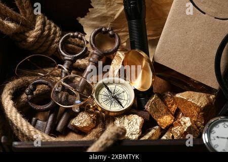 Scatola di legno con attrezzatura da viaggio, pepite dorate e bottiglia di rum, primo piano Foto Stock