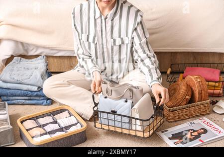 Donna con accessori e abiti eleganti seduti sul pavimento Foto Stock