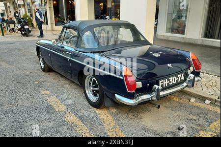 Roadster MG MGB 1970-S blu scuro parcheggiato sul marciapiede, vista dall'angolo posteriore sinistro Foto Stock