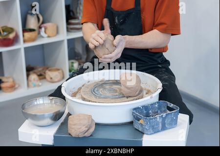 Il vasaio impastò l'argilla prima di usarla sulla ruota del vasaio. Primo piano delle mani di un uomo. Foto Stock