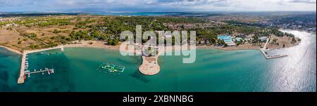 Zaton, Croazia - Vista panoramica aerea del lungomare turistico di Zaton con acque turchesi, villaggio di Nin e montagne di Velebit sullo sfondo su un sole Foto Stock