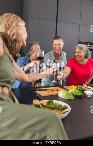 Gruppo di diverse donne anziane che si godono il vino e ridono insieme Foto Stock