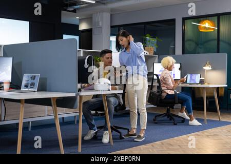 Un gruppo diversificato di colleghi aziendali collabora in un ufficio moderno, uno con un tablet Foto Stock