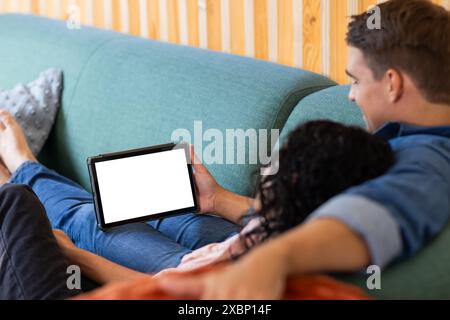 Coppie diverse che si rilassano sul divano, guardano il tablet insieme, copiano spazio Foto Stock