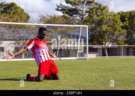 Giocatore di calcio afroamericano che festeggia sul campo di calcio, sembra forte e in forma, copia spazio Foto Stock