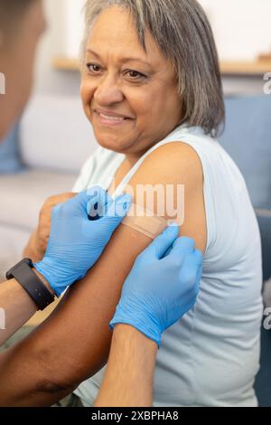 Un giovane infermiere birazziale che bendava paziente anziano birazziale femminile Foto Stock