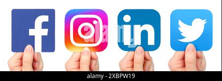Set di mani, che tengono in mano icone cartacee di popolari app di social media, come: Facebook, Instagram, LinkedIn e Twitter, isolate su una ba trasparente Foto Stock