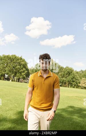 Un uomo con una polo gialla cammina con grazia in un campo vivace. Foto Stock