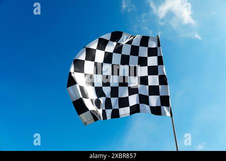 Una bandiera a scacchi contro il cielo blu all'aperto Foto Stock