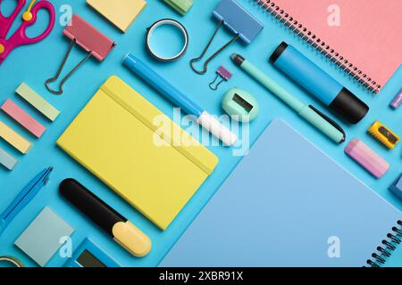 Composizione piatta con quaderno e cancelleria diversa su sfondo azzurro Foto Stock