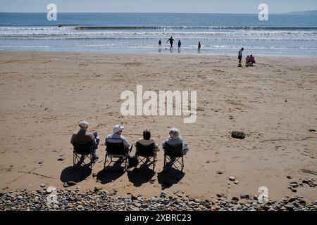 Quattro pensionati sedevano di fila sulla spiaggia al largo di Cobble Landing a Filey, North Yorkshire East Coast, Inghilterra settentrionale, Regno Unito Foto Stock