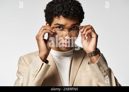 Giovane uomo in abito abbronzato che indossa occhiali eleganti. Foto Stock