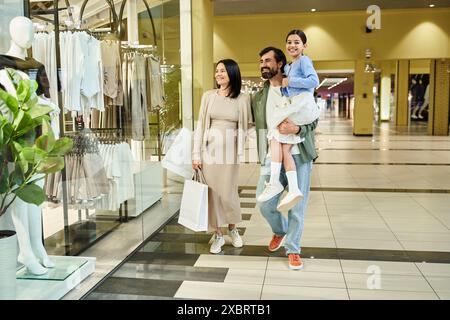 Una famiglia felice, genitori e bambini, passeggia in un vivace centro commerciale per un fine settimana. Foto Stock