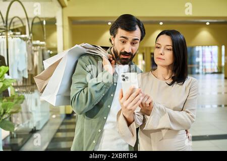 Un uomo e una donna travolti da un cellulare in un vivace centro commerciale. Foto Stock