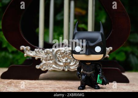 Funko Pop action figure del supereroe DC Batman Bruce Wayne che tiene in mano la scheda messaggi dell'Enigmista. Gazebo in miniatura, palazzo con colonne. Foto Stock