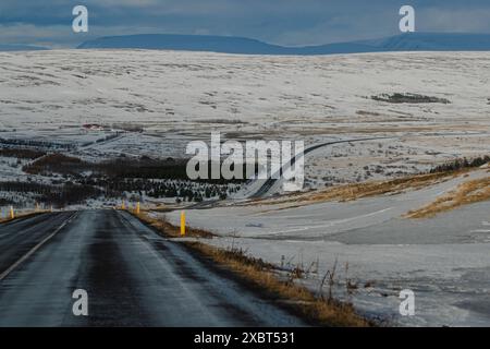 Strada innevata che conduce a un vasto paesaggio invernale Foto Stock