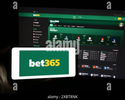 Persona con smartphone con logo della società britannica di scommesse sportive Bet365 davanti al sito Web. Mettere a fuoco il display del telefono. Foto Stock