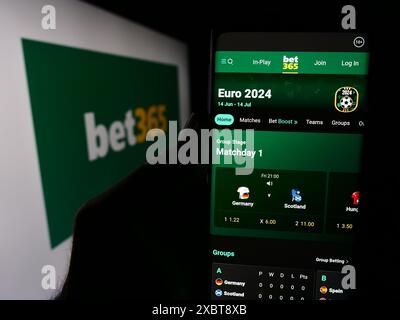 Persona che detiene un cellulare con pagina web della società britannica di scommesse sportive Bet365 davanti al logo aziendale. Messa a fuoco al centro del display del telefono. Foto Stock