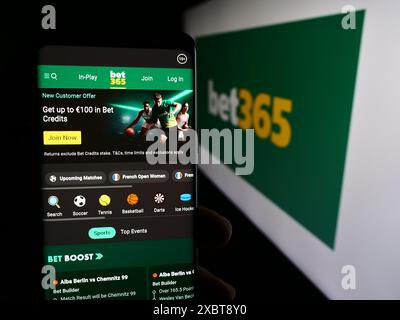 Persona che detiene lo smartphone con la pagina web della società britannica di scommesse sportive Bet365 davanti al logo aziendale. Messa a fuoco al centro del display del telefono. Foto Stock