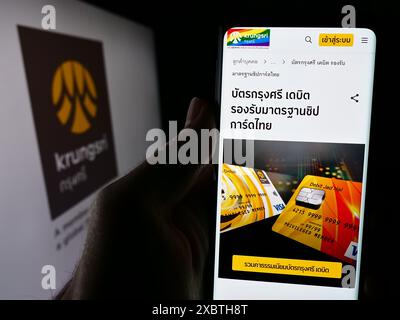 Persona che detiene lo smartphone con pagina web della Thai Bank of Ayudhya Public Company Limited (Krungsri) con logo. Messa a fuoco al centro del display del telefono. Foto Stock