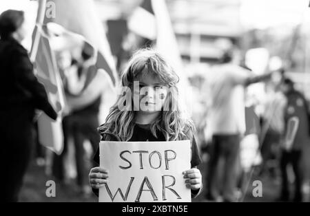 Ritratto di bambino ragazzo chiama a fermare la guerra in Ucraina, tenendo un poster con Stop il messaggio di guerra in piedi all'aperto. Aggressione russa. Il bambino porta un Foto Stock