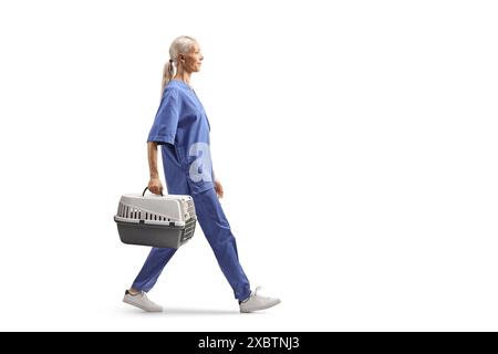 Veterinario femminile in uniforme blu, in possesso di un trasportino per animali domestici e isolata a piedi su sfondo bianco Foto Stock