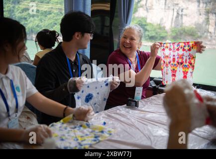 (240613) -- WUHAN, 13 giugno 2024 (Xinhua) -- partecipanti che partecipano a un programma di scambio giovanile Cina-Stati Uniti sperimentano il tie-dye a bordo di una nave turistica elettrica a Yichang, nella provincia di Hubei della Cina centrale, 11 giugno 2024. Un gruppo di giovani americani e cinesi ha completato un avventuroso viaggio estivo nella provincia di Hubei della Cina centrale, immergendosi nelle antiche tradizioni e nella modernità della cultura cinese in una settimana ricca di azione. Dal 6 al 12 giugno, oltre 40 partecipanti di università, imprese e organizzazioni sociali hanno preso parte a un programma di scambio giovanile Cina-Stati Uniti Foto Stock