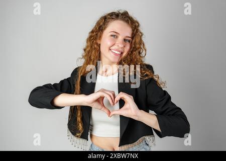 Donna che fa il cuore con le mani in Studio Foto Stock