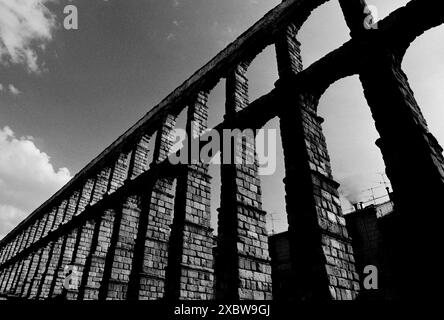 Segovia , ponte dell'acquedotto su plaza del Azoguejo, Spagna l'acquedotto di Segovia (spagnolo: Acueducto de Segovia) è un acquedotto romano situato a Segovia, Spagna. Fu costruito intorno al i secolo d.C. per incanalare l'acqua dalle sorgenti delle montagne a 17 chilometri di distanza fino alle fontane della città, ai bagni pubblici e alle case private, e fu in uso fino al 1973. La sua sezione sopraelevata, con la sua arcata completa di 167 archi, è uno dei ponti dell'acquedotto romano meglio conservati e il simbolo principale di Segovia, come dimostra la sua presenza sullo stemma della città. Il centro storico di Segovia e l'acquedotto, Foto Stock