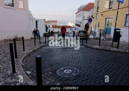 Alfama durante le popolari festività dei santi: Una persona su un segway naviga in una tortuosa strada acciottolata Foto Stock