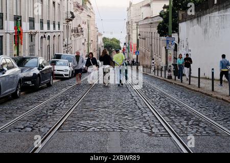 Alfama durante le feste popolari dei santi. La gente cammina lungo rua da voz do Operário, una strada in pendenza con binari del tram Foto Stock