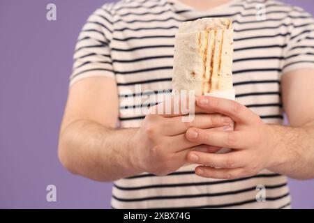 Uomo con kebab donatore su sfondo viola Foto Stock