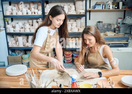 Donne che producono piatti di argilla in un laboratorio di ceramica Foto Stock