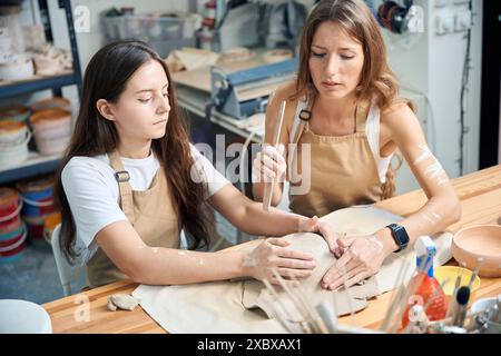 Le femmine producono piatti artigianali in un laboratorio di ceramica professionale Foto Stock