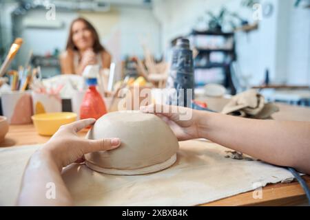 Donna irriconoscibile che scolpisce la ciotola di argilla in officina Foto Stock