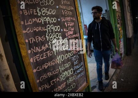 Buenos Aires, Argentina. 1 giugno 2024. Un uomo esce da un negozio di alimentari e passa davanti a un cartello con i prezzi della carne. A maggio, i prezzi sono aumentati del 4,2% nel paese sudamericano, colpito da una grave crisi economica. Il tasso annuo di inflazione è del 276,4%. Crediti: Cristina Sille/dpa/Alamy Live News Foto Stock