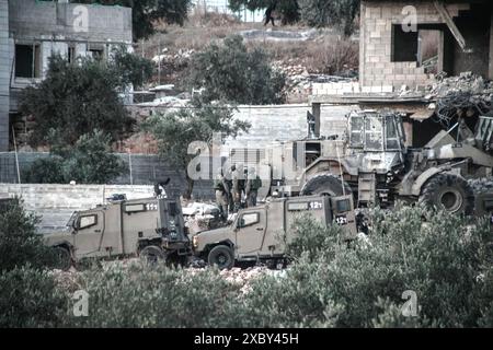 Jenin, Palestina. 13 giugno 2024. Le forze israeliane e i bulldozer hanno circondato la casa dove i combattenti della resistenza palestinese sono stati barricati nella città di Qabatiya vicino a Jenin in Cisgiordania durante un'operazione militare. Dopo un raid da parte delle forze israeliane, l'assassinio di due palestinesi. (Foto di Nasser Ishtayeh/SOPA Images/Sipa USA) credito: SIPA USA/Alamy Live News Foto Stock