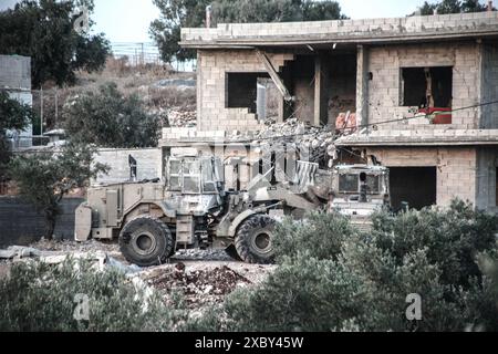 Jenin, Palestina. 13 giugno 2024. I bulldozer israeliani demoliscono una casa in cui i combattenti della resistenza palestinese sono stati barricati nella città di Qabatiya vicino a Jenin in Cisgiordania durante l'operazione militare. Dopo un raid da parte delle forze israeliane, l'assassinio di due palestinesi. (Foto di Nasser Ishtayeh/SOPA Images/Sipa USA) credito: SIPA USA/Alamy Live News Foto Stock