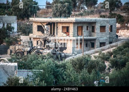 Jenin, Palestina. 13 giugno 2024. Le forze israeliane e i bulldozer hanno circondato la casa dove i combattenti della resistenza palestinese sono stati barricati nella città di Qabatiya vicino a Jenin in Cisgiordania durante un'operazione militare. Dopo un raid da parte delle forze israeliane, l'assassinio di due palestinesi. (Foto di Nasser Ishtayeh/SOPA Images/Sipa USA) credito: SIPA USA/Alamy Live News Foto Stock