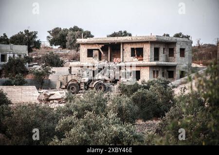 Jenin, Palestina. 13 giugno 2024. I bulldozer israeliani demoliscono una casa in cui i combattenti della resistenza palestinese sono stati barricati nella città di Qabatiya vicino a Jenin in Cisgiordania durante l'operazione militare. Dopo un raid da parte delle forze israeliane, l'assassinio di due palestinesi. (Foto di Nasser Ishtayeh/SOPA Images/Sipa USA) credito: SIPA USA/Alamy Live News Foto Stock