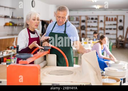 potter lavora con il rullo pressa per argilla della macchina per studenti Foto Stock