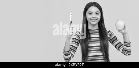 Seguire l'igiene orale. Ragazza felice tenere mela e spazzolino da denti. Igiene orale. Cura dentale. Banner di bambina con pennello denti, ritratto studio, intestazione Foto Stock