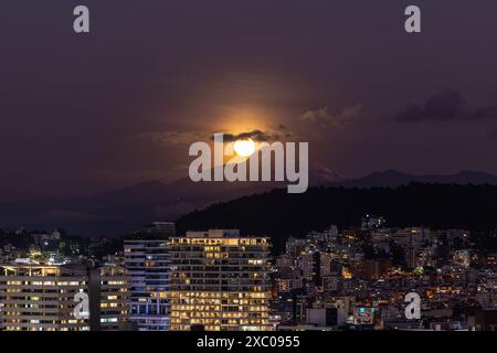 Luna llena brillante saliendo atras del volcan Cayambe en Quito Foto Stock