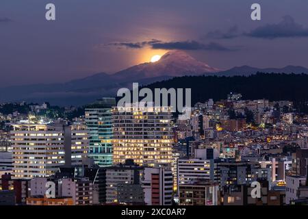 La luna aparece poco a poco muy brillante atras del volcan Cayambe en Quito Foto Stock