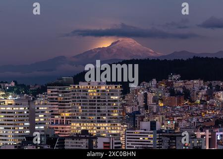 Resplandor de luz de la luna saliendo atrás del Volcán Cayambe al anochecer Foto Stock