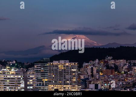 Resplandor de luz de la luna saliendo atrás del Volcán Cayambe al anochecer Foto Stock